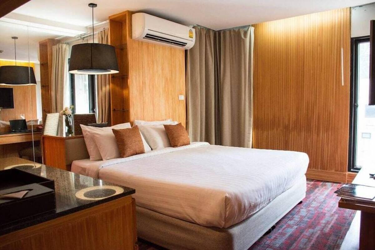 A hotel room with a large bed, wooden paneling, a flat-screen TV, and a desk with a chair.