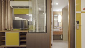 Een hotelkamer met een televisie, airconditioning en uitzicht op de badkamer.