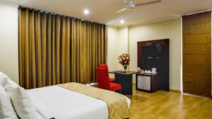 A hotel room with a bed, a desk, a chair, a TV, and a wardrobe. - Clarks Inn Nehru Place (New Delhi)