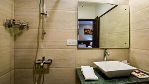 A bathroom with a shower, a sink, a mirror, and a towel on the counter. - Clarks Inn Nehru Place (New Delhi)