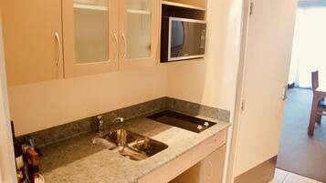 A kitchen with a granite countertop, stainless steel sink, and a microwave.