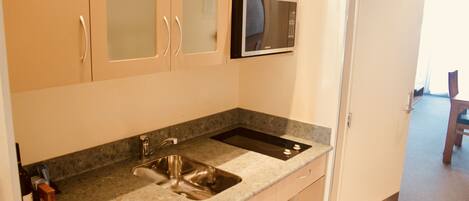 A kitchen with a granite countertop, stainless steel sink, and a microwave.