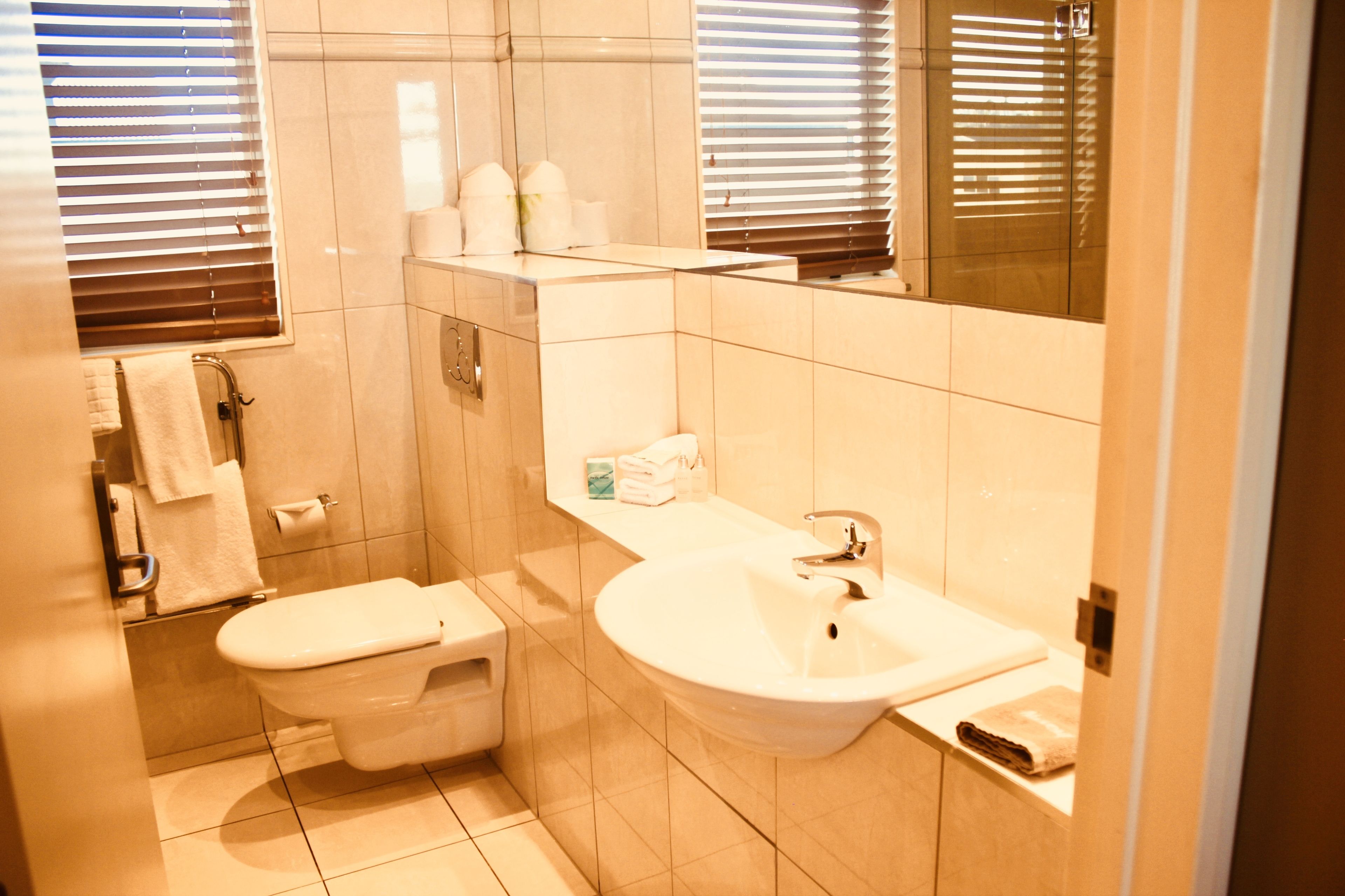 A small bathroom with a toilet, sink, and mirror.