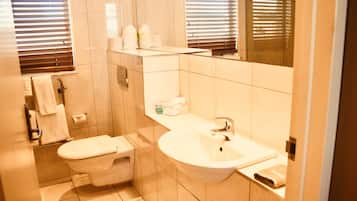 A small bathroom with a toilet, sink, and mirror.