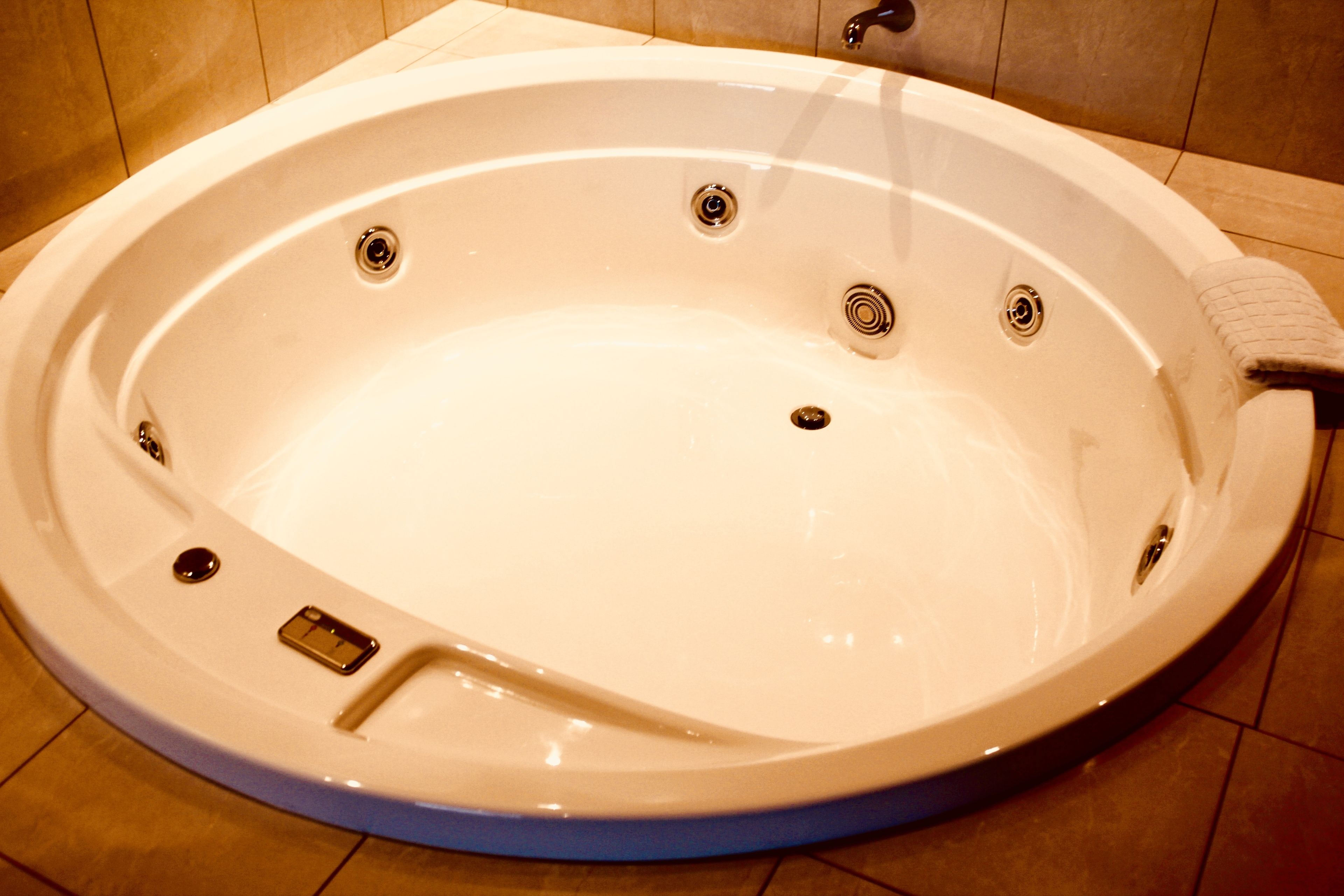A large, oval-shaped hot tub with multiple drain holes and a built-in seat.