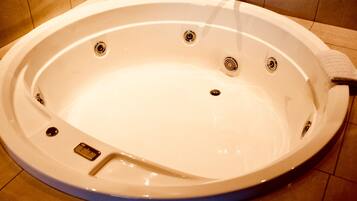 A large, oval-shaped hot tub with multiple drain holes and a built-in seat.