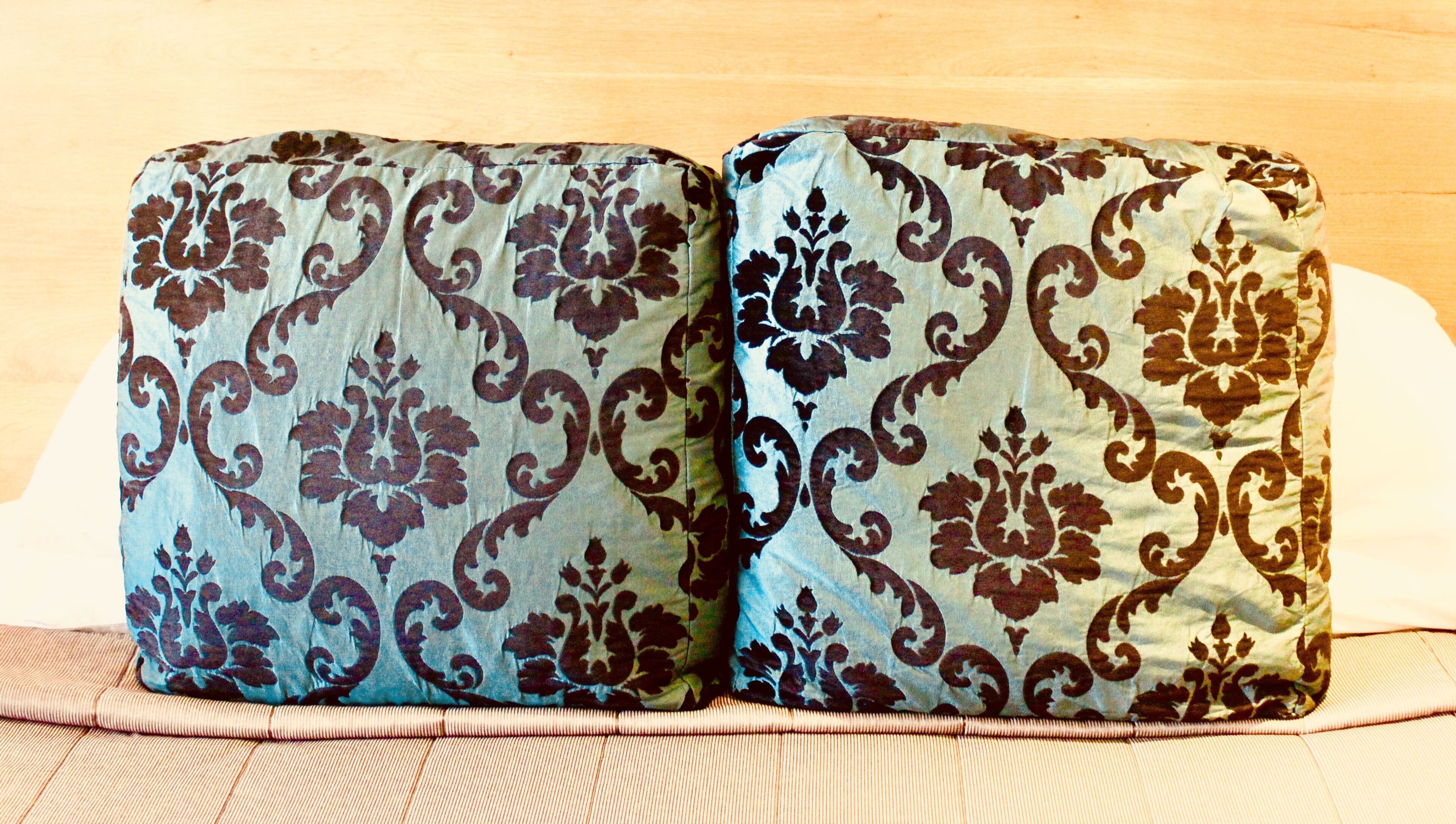 Zwei Kissen mit Paisleymuster auf einem Bett.