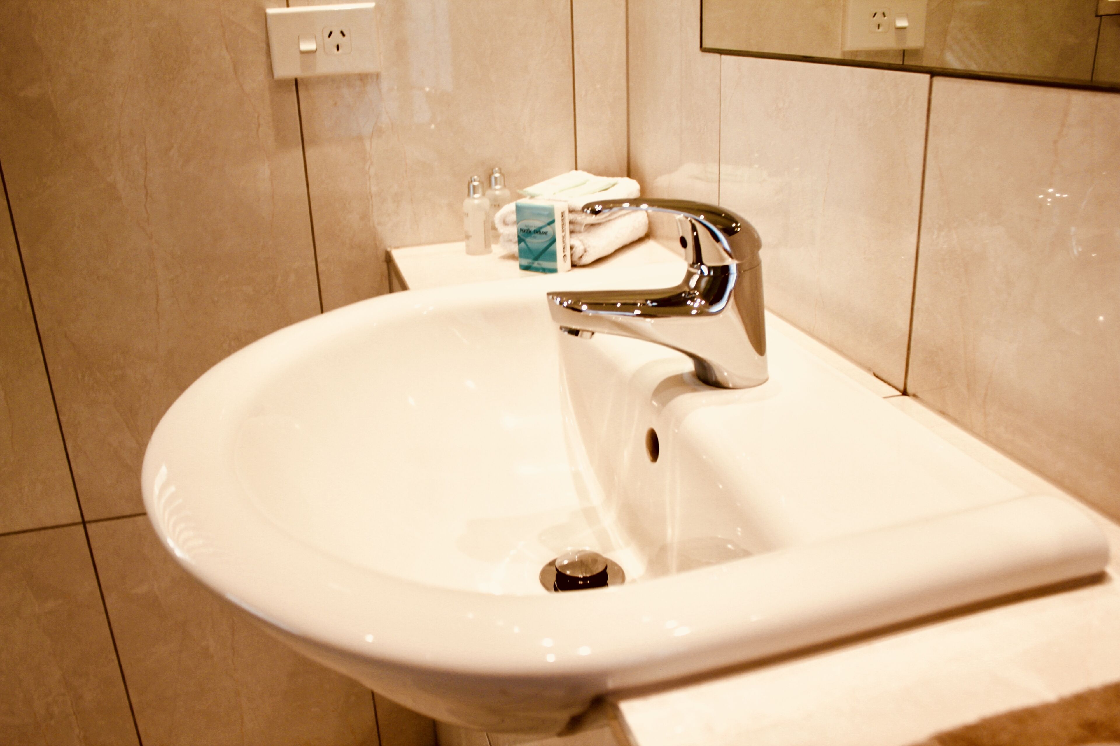A bathroom sink with a chrome faucet, a mirror above it, and a towel rack with towels.