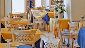 Um restaurante com várias mesas e cadeiras, tetos abobadados e diversos objetos decorativos nas paredes.