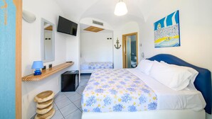Quarto com cama, televisão, micro-ondas, prateleira de madeira e porta para um banheiro.
