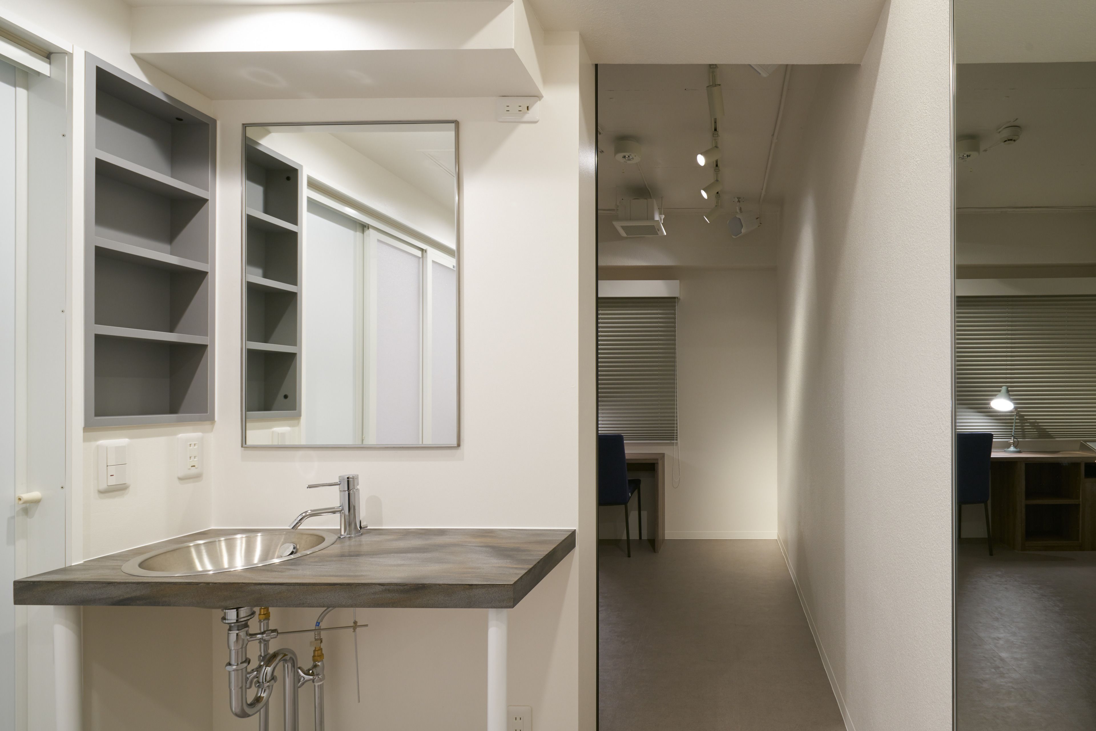 A modern bathroom with a large mirror, a sink, and a shower area.
