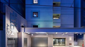 A modern building with a tiled facade, a large garage door, and a well-lit entrance area. - City Hotel N.U.T.S. (Tokyo)