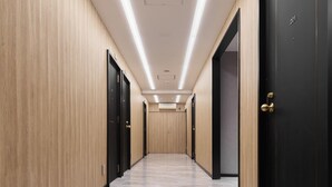 A hallway with wooden panel walls, black doors, and a marble floor. - City Hotel N.U.T.S. (Tokyo)