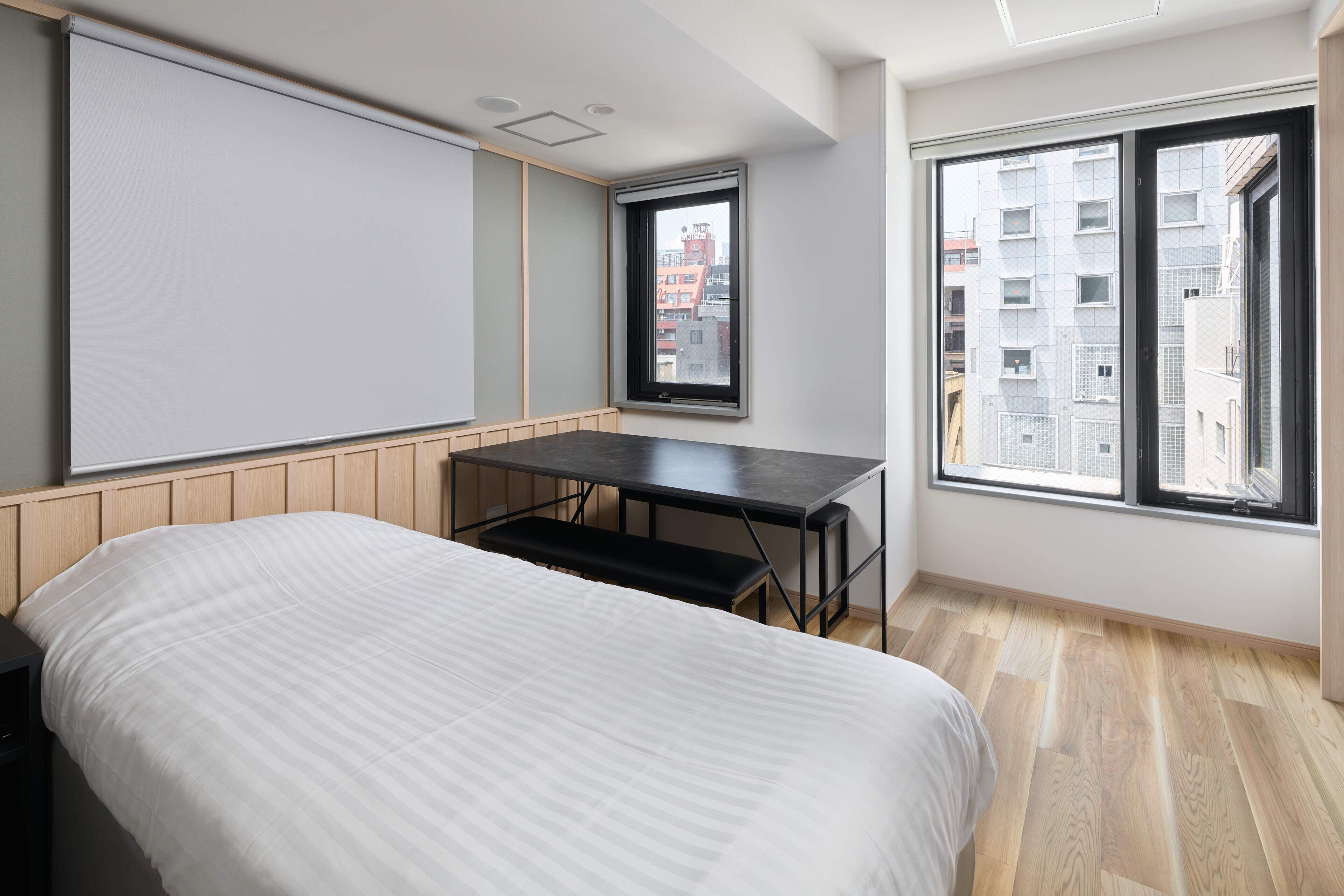 A bedroom with a bed, a desk, and a window.