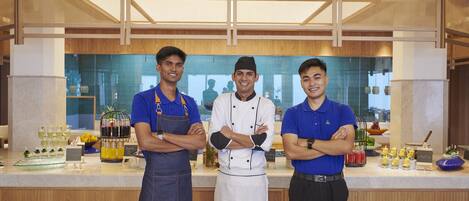 Tres empleados en un área de cocina moderna con paneles de madera y una división de vidrio.