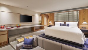A modern hotel room with a large bed, a flat-screen TV, a desk, and a seating area. - Athiva Resort & Spa, Khandala (Mawal)