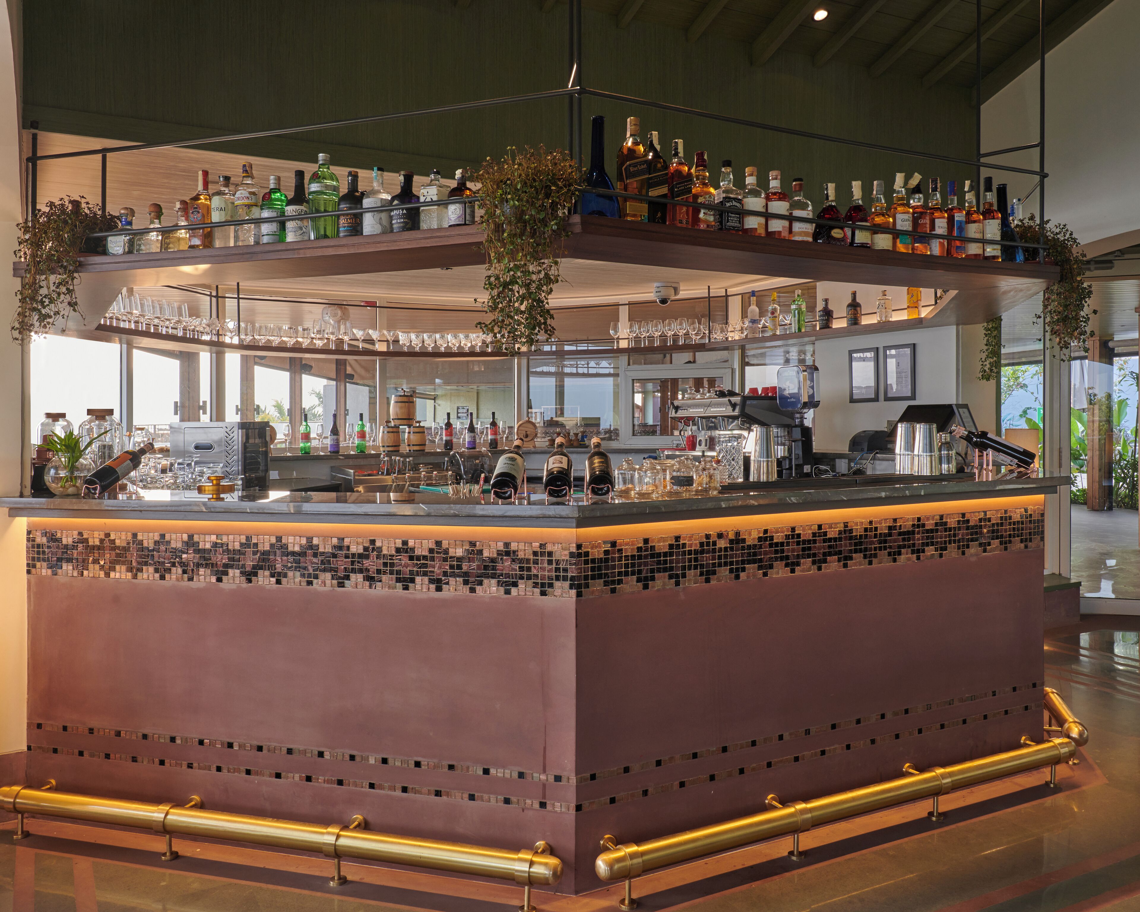 A bar area with multiple shelves of bottles, glasses, and a coffee machine.