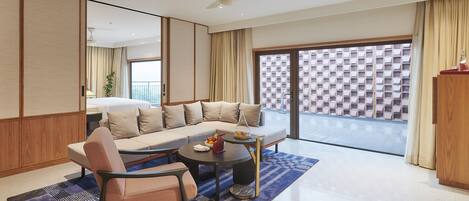 Una sala de estar moderna con sofá, sillón, mesa de centro y vistas a un balcón.