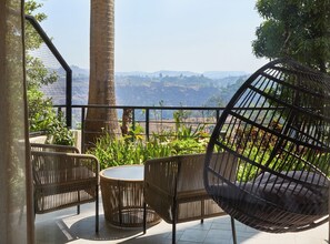A terrace with wicker furniture, a round table, and a view of a mountainous landscape. - Athiva Resort & Spa, Khandala (Mawal)
