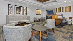 Een moderne hotellobby met een zithoek, een receptiebalie en kunstwerken aan de wanden.
