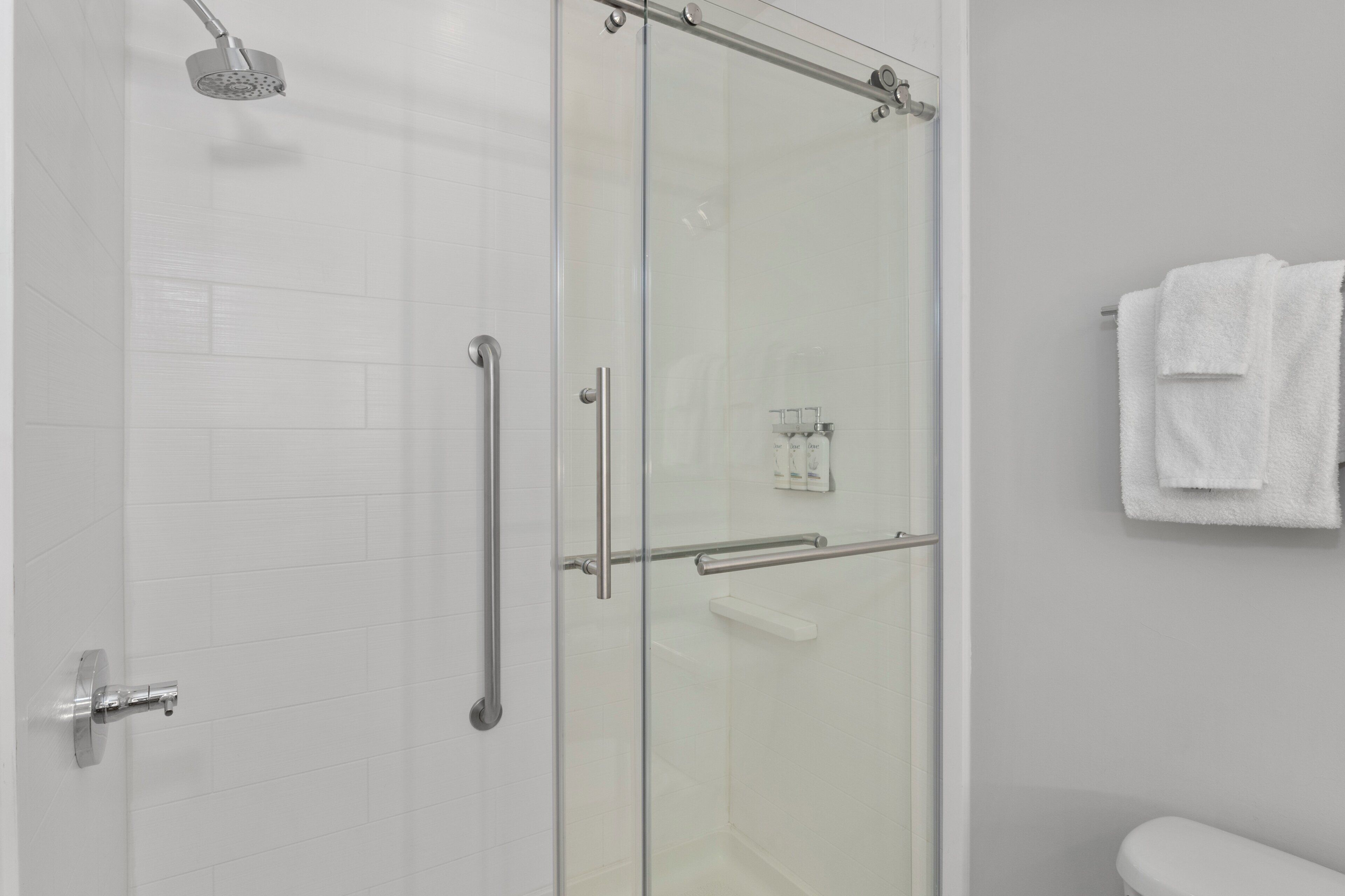 A modern bathroom with a glass shower enclosure, a toilet, and a towel rack.
