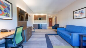 A modern apartment with a kitchenette, a dining area, a living room with a blue sofa, and a workspace with a desk and chair. - Holiday Inn Express Johnson City by IHG (Johnson City)