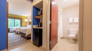 Een hotelkamer met een bed, een kleine kitchenette, een magnetron en een badkamer met toilet en douche.