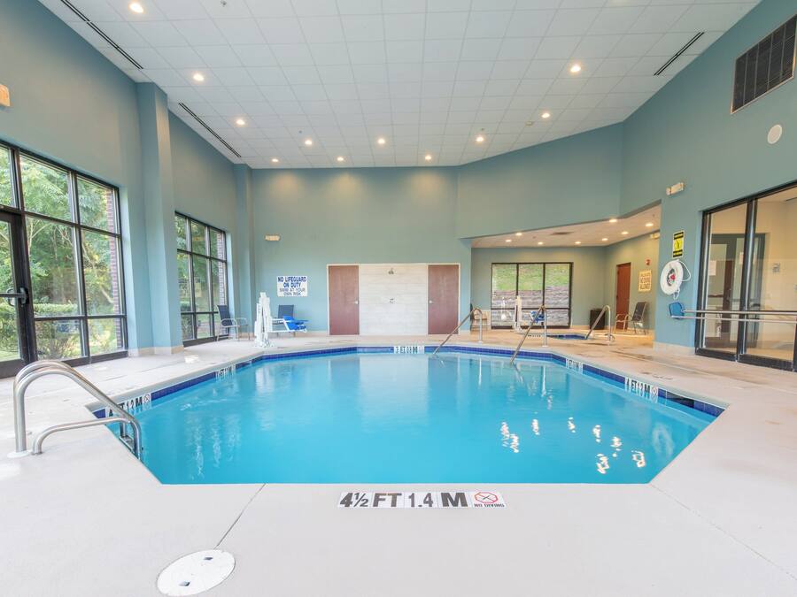 Una piscina interior con agua cristalina, líneas de profundidad marcadas y un cartel de prohibido bucear.
