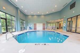 Piscina interna com água cristalina, linhas de profundidade marcadas e placa de proibição de mergulho.