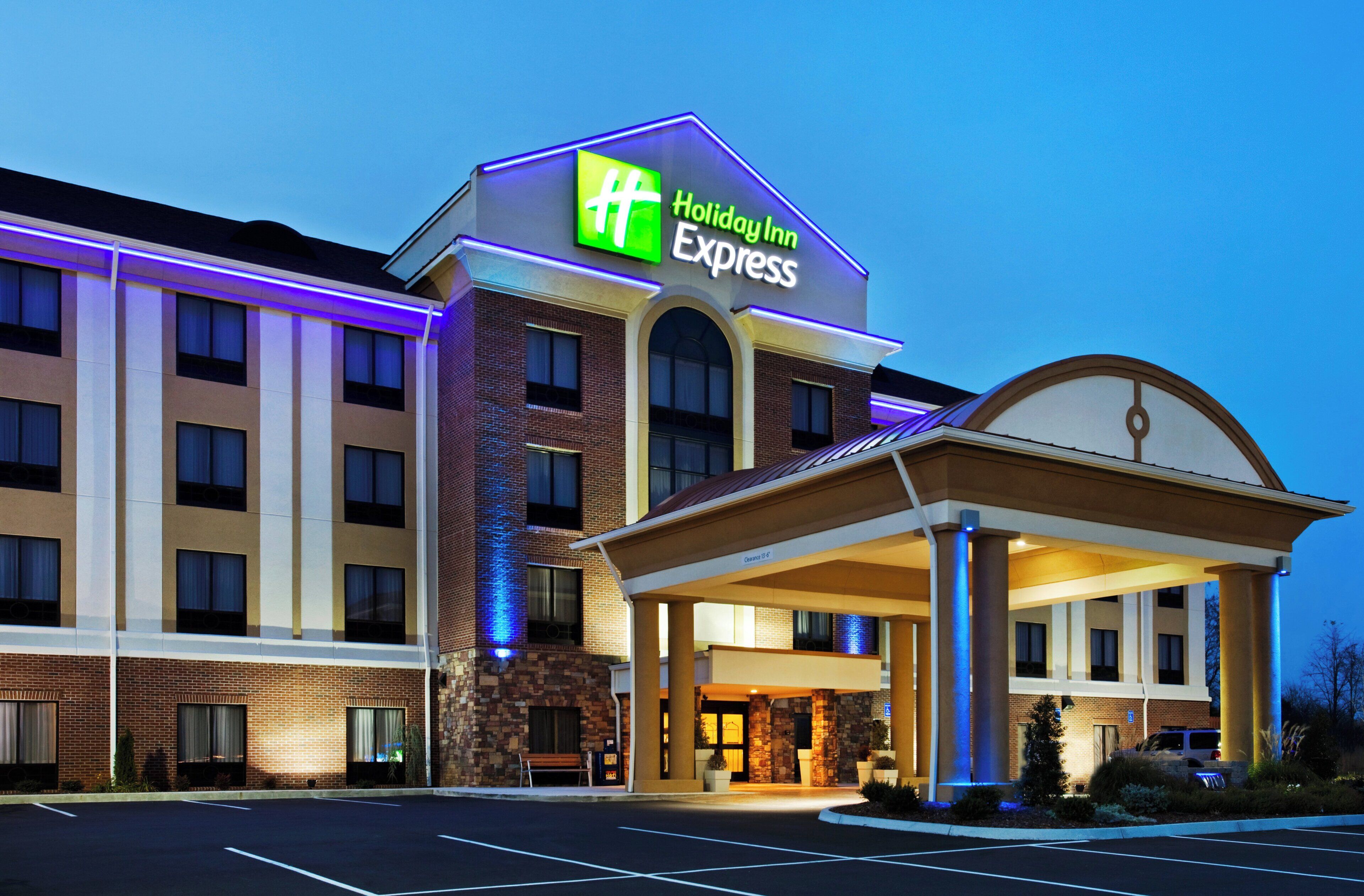 Een Holiday Inn Express gebouw met een bakstenen gevel, een overdekte ingang en een parkeerplaats.