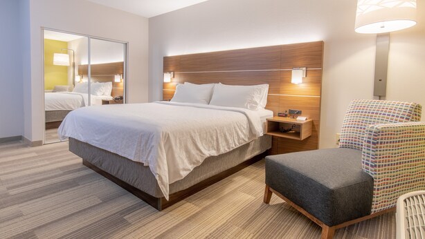 A modern hotel room with a large bed, bedside tables, a chair, and a mirror. - Holiday Inn Express Johnson City by IHG (Johnson City)