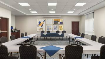 A conference room with a long table, multiple chairs, and artwork on the walls.