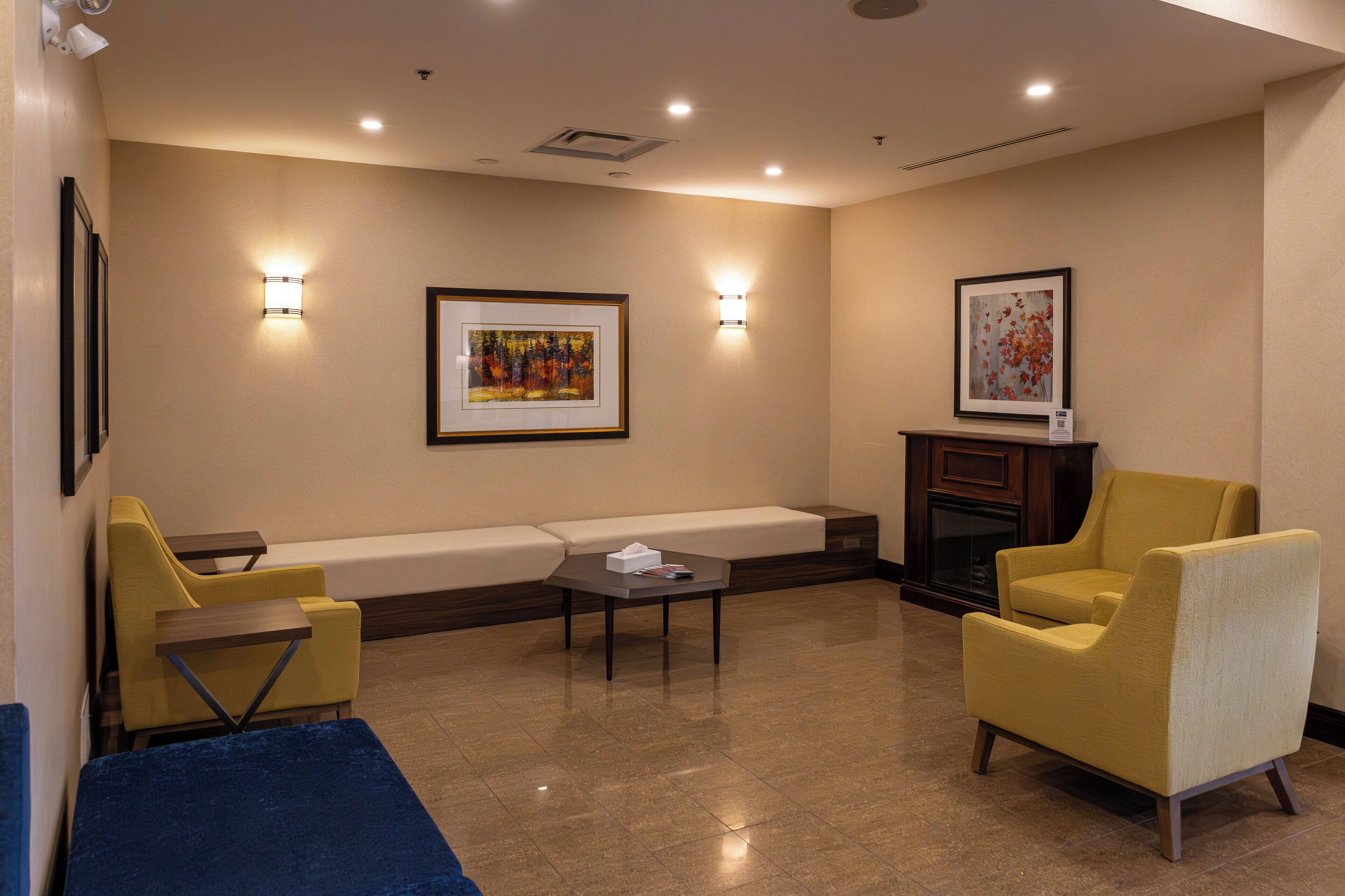 Un área de estar moderna con un sofá, dos sillones, una mesa de centro y una chimenea.