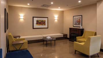 A modern lounge area with a sofa, two armchairs, a coffee table, and a fireplace.