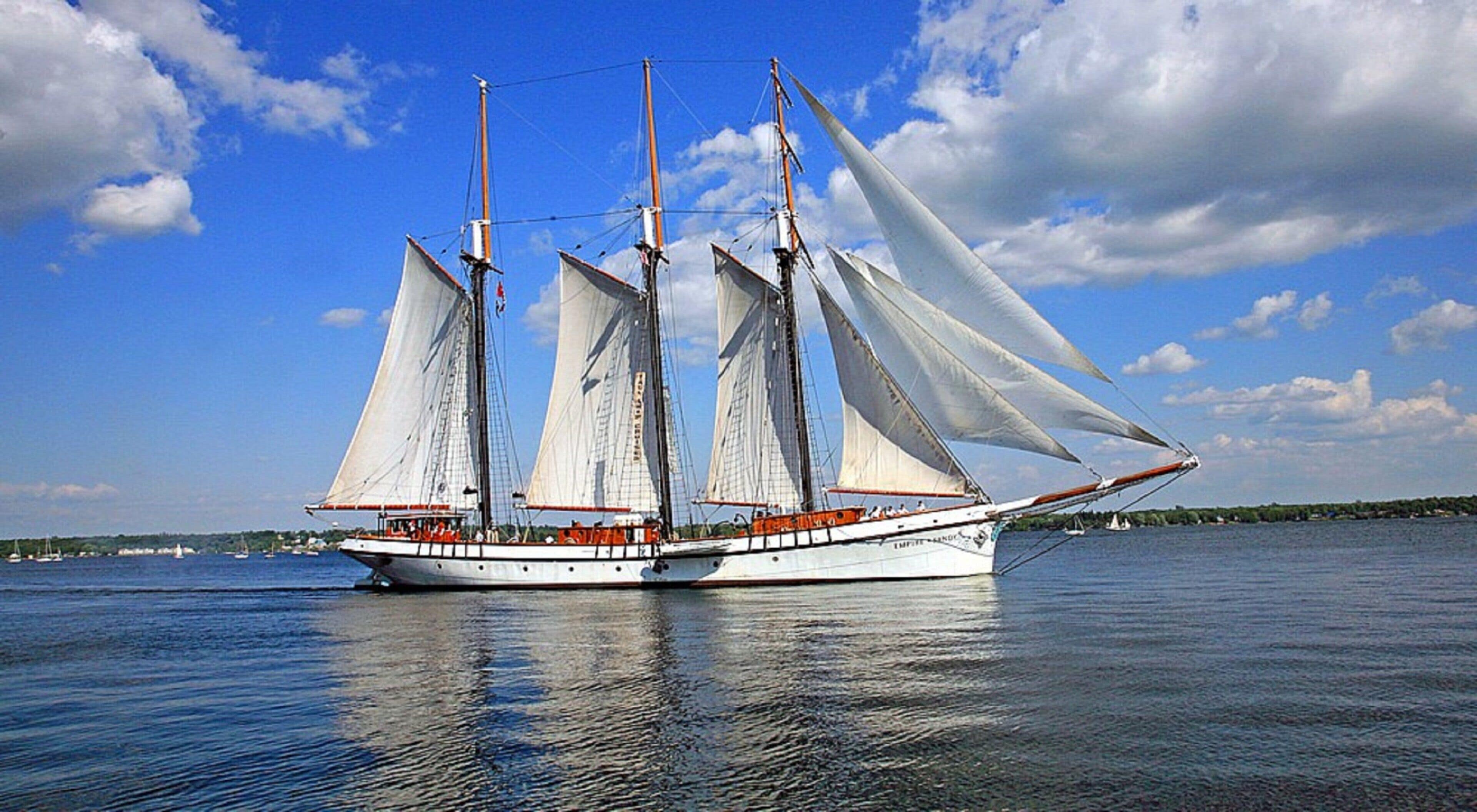 A large sailing ship with multiple masts and sails, anchored in calm waters.