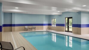 Ein Hallenbad mit blau-weißen Fliesen, klares Wasser und eine Tür, die nach draußen führt.