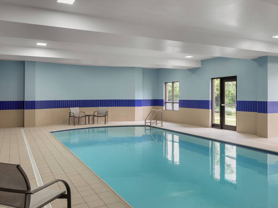 An indoor swimming pool with blue and white tiled walls, a clear pool, and a door leading outside.