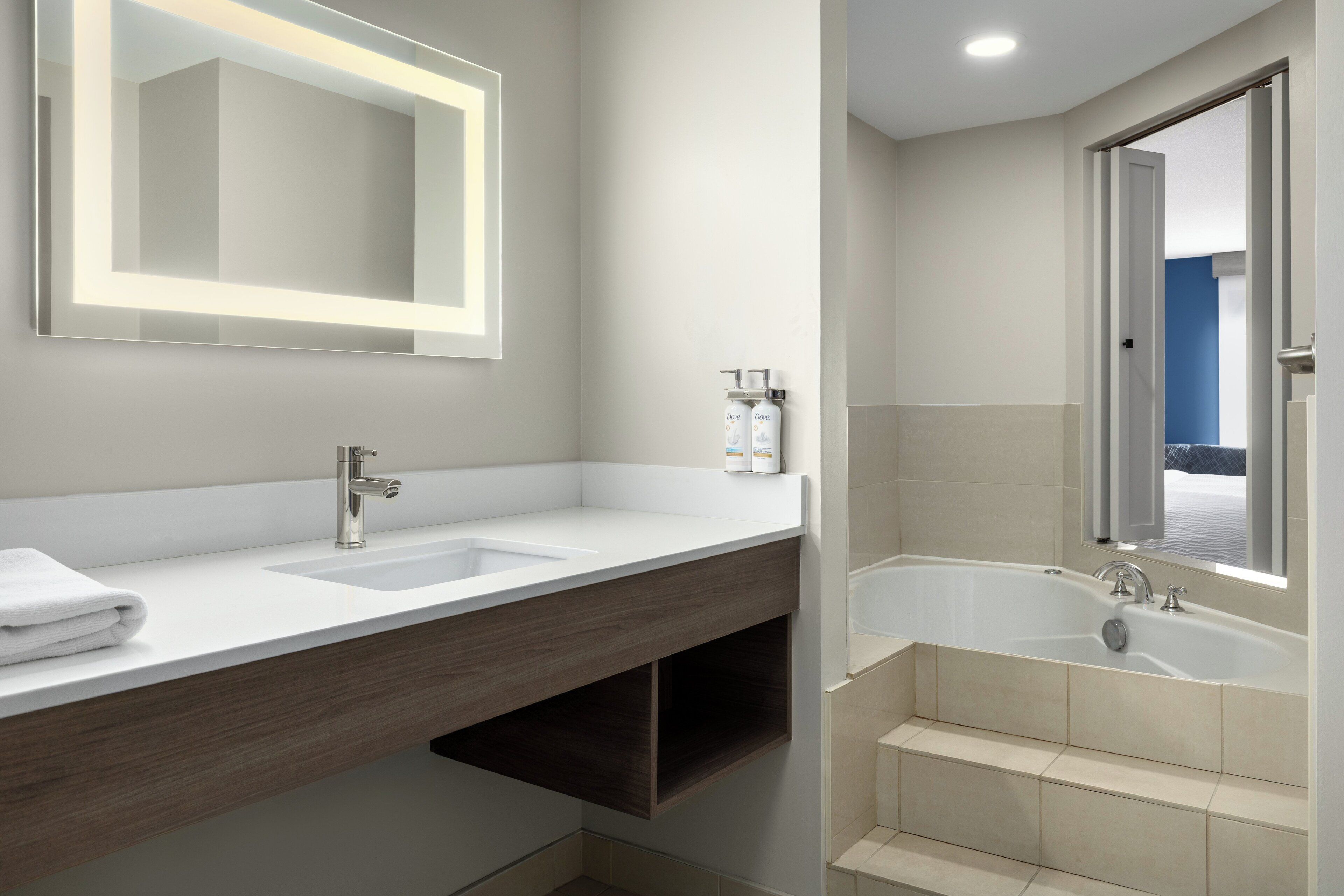 A modern bathroom with a double sink vanity, a large mirror, and a freestanding bathtub.