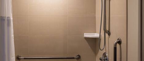 A modern bathroom with a bathtub, shower, and grab bars.