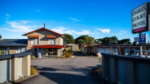 A motel with a red roof and a sign indicating it is Charles Court Motel. - Charles Court Motel (Greymouth)