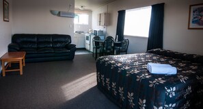 A hotel room with a bed, a sofa, a desk, and a chair. - Charles Court Motel (Greymouth)