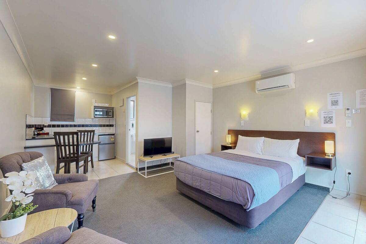 Une chambre d’hôtel équipée d’un lit, d’un bureau, d’une chaise, d’une télévision et d’une kitchenette.
