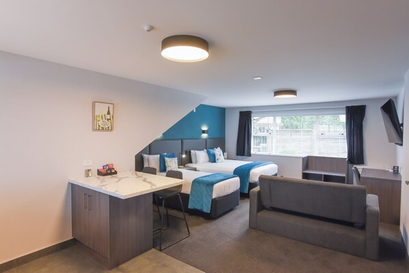 Habitación de hotel con cama, escritorio, silla y ventana con persianas.