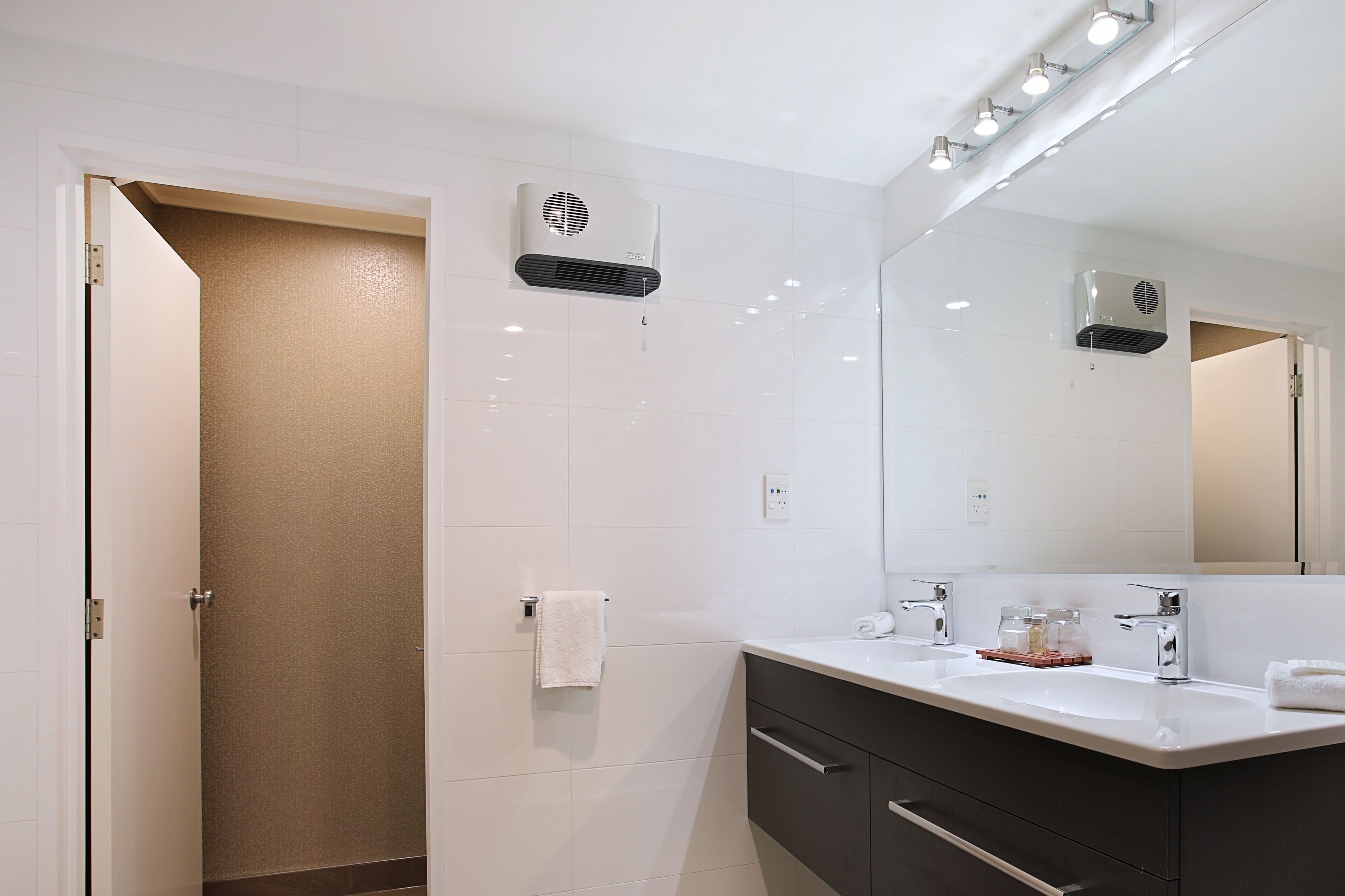 Une salle de bain moderne avec un meuble-lavabo blanc, un grand miroir et un porte-serviettes.