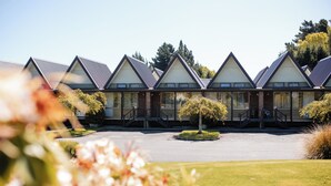 A row of modern, triangular-roofed buildings with large windows, a central courtyard, and surrounding greenery. - Ascot Park Hotel (Invercargill)
