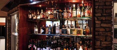 A bar with multiple shelves of various liquor bottles and glasses.