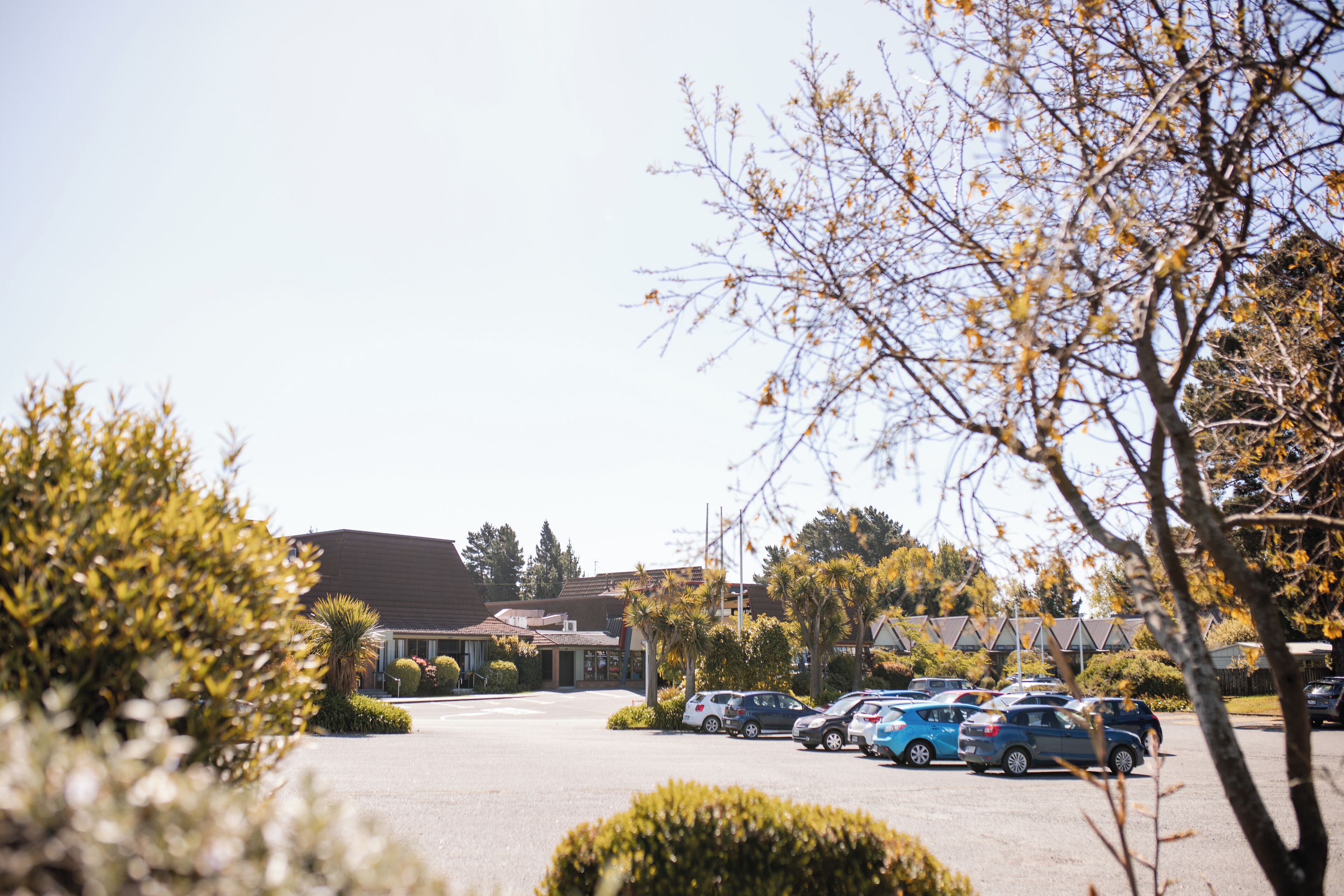 A parking lot with several cars, surrounded by trees and buildings.