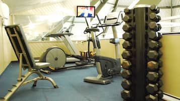 Uma academia com equipamentos de exercícios, incluindo esteira, elíptico e aparelho de musculação.