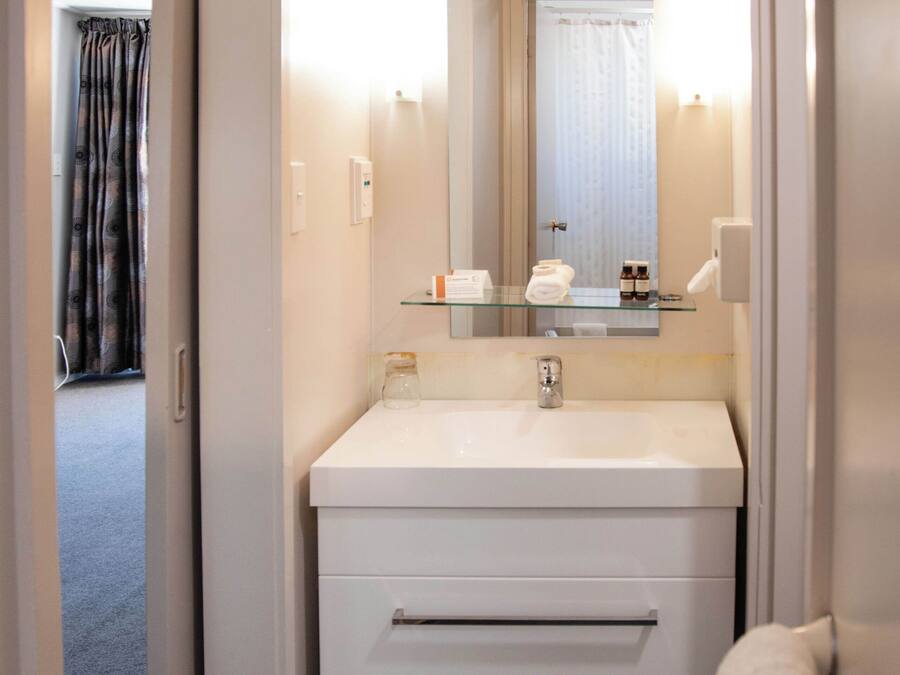 A hotel bathroom with a white sink, a mirror, and a towel rack.