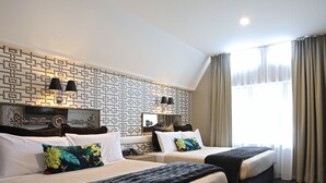 A hotel room with two beds, a patterned wall, and a large window with curtains. - Ascot Park Hotel (Invercargill)